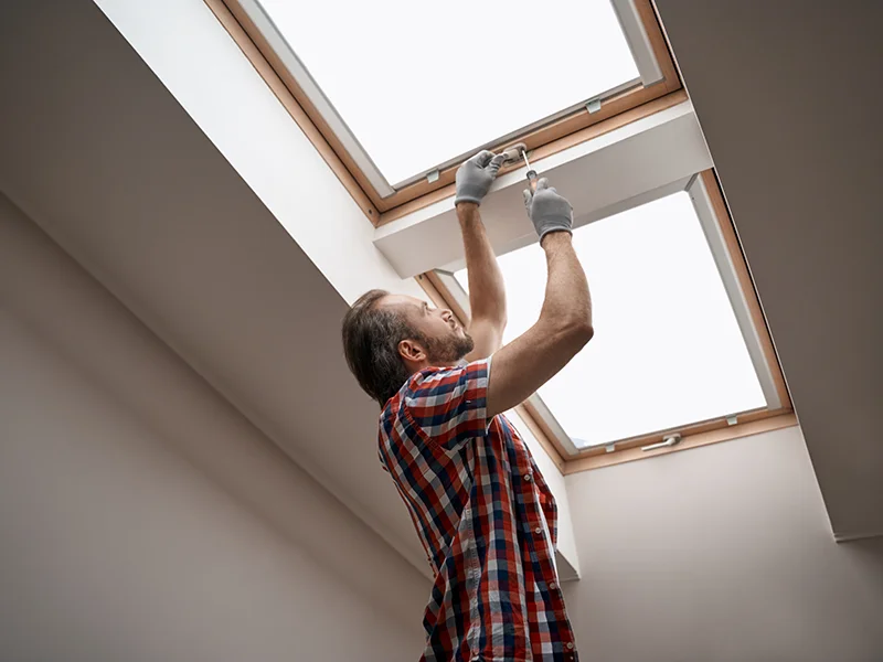 Worker installing a skylight from inside a home